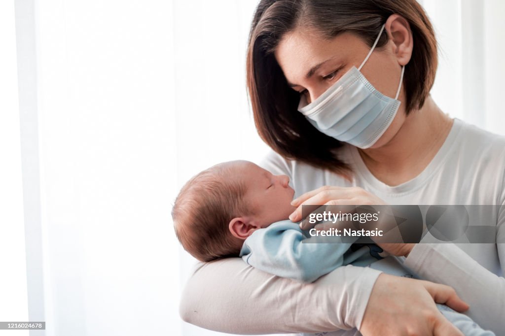 Mother with protective mask holding baby