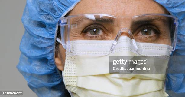 serious, overworked, female health care worker - face mask protective workwear imagens e fotografias de stock