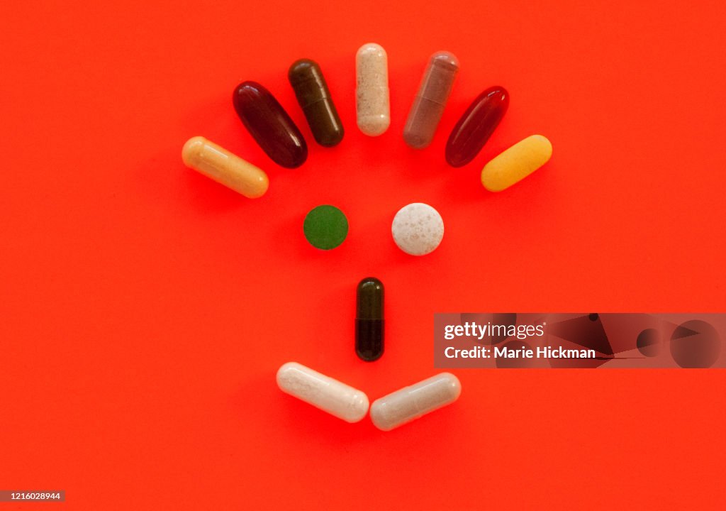 Face made out of vitamins on an orange background.