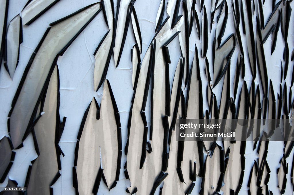Sun-damaged pale blue plastic film peeling off stainless steel