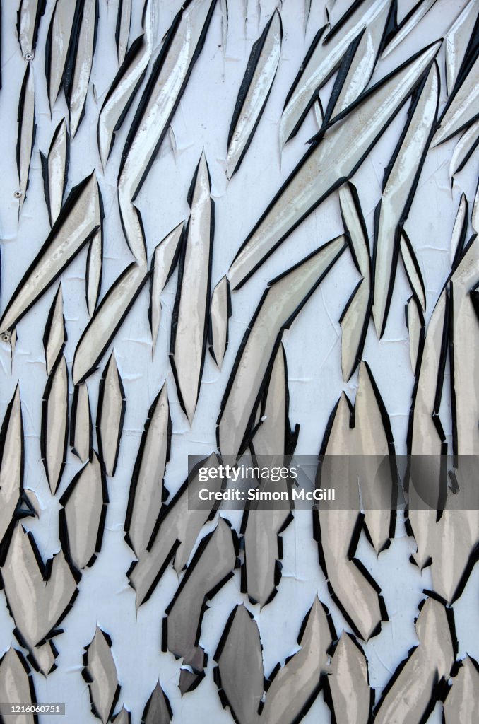 Sun-damaged pale blue plastic film peeling off stainless steel