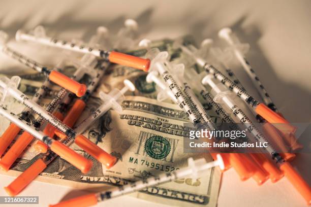 syringes covering two twenty dollar bills - opioid epidemic stock pictures, royalty-free photos & images