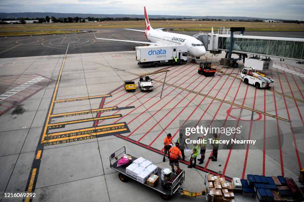 Baggage handers load a Qantas plane at Adelaide Airport on April 01, 2020 in Adelaide, Australia. The Australian government has introduced further...