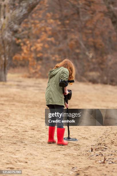 jong meisje dat metaaldetector in zand bij strand gebruikt - schatzoeken stockfoto's en -beelden