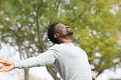 Black man breathing fresh air stretching arms in a park