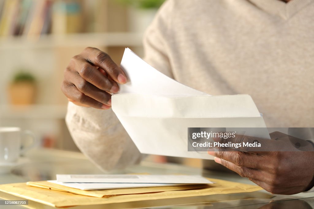 Black man hands putting a letter inside an envelope