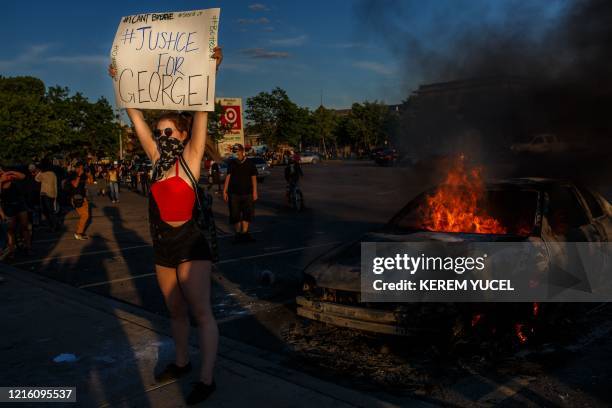 Protester hold sign board "Justice for George" into a fire outside a Target store near the Third Police Precinct on May 28, 2020 in Minneapolis,...