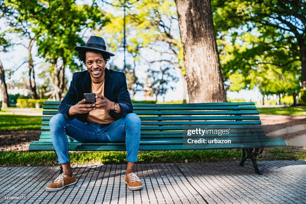 Uomo sorridente con telefono in panchina
