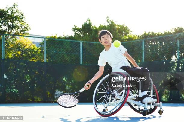 young male in a wheelchair playing tennis on a tennis court - rollstuhltennis stock-fotos und bilder