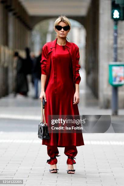 Influencer Gitta Banko, wearing a dress over pants look with a red oversized blouse, a red flared medi dress and red satin pants by Liviana Conti, a...