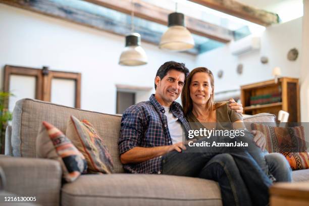 relaxed mature couple sitting close on sofa in family home - two houses side by side stock pictures, royalty-free photos & images