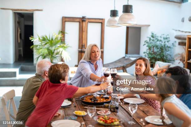 mujer senior de pie para brindar con los miembros de la familia - cultura mediterránea fotografías e imágenes de stock