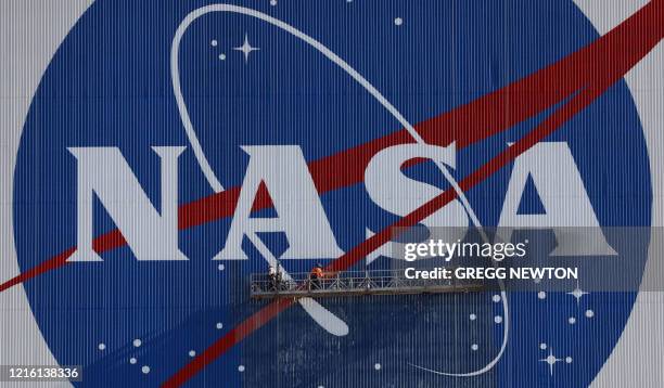 Painters refurbish the NASA logo on the Vehicle Assembly Building at the Kennedy Space Center in Florida in Florida on May 29, 2020. The faded...