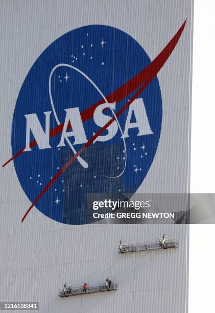 Painters refurbish the NASA logo on the Vehicle Assembly Building at the Kennedy Space Center in Florida in Florida on May 29, 2020. The faded...