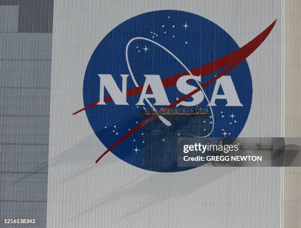 Painters refurbish the NASA logo on the Vehicle Assembly Building at the Kennedy Space Center in Florida in Florida on May 29, 2020. The faded...
