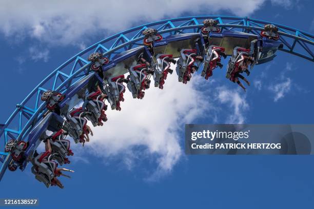 People wearing protective masks enjoy the Blue Fire roller coaster at Europa-Park, Germany's largest theme park, in Rust, on May 29, 2020 during the...