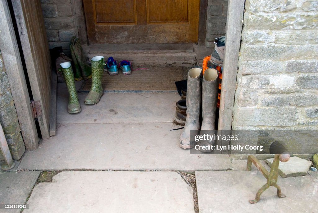 Muddy wellington rubber boots on stone doorstep