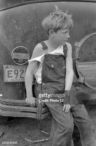 Child of white migrant worker sitting on bumper of their car from Arizona, near Harlingen, Texas by Russell Lee, 1903-1986, dated 1939.
