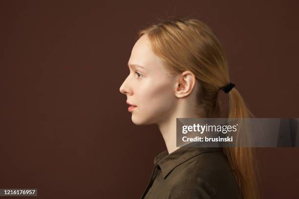 retrato de estudio de una mujer de 25 años sobre fondo marrón - cola de caballo cabello recogido fotografías e imágenes de stock
