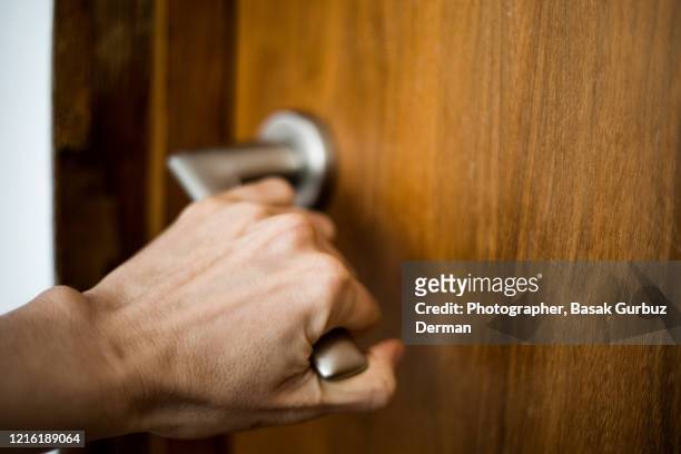 a hand holding the doorknob, opening / closing a door - chiuso foto e immagini stock