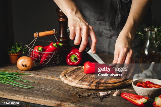 frau schneidet chilischoten, um rote pfeffersuppe vorzubereiten - pepper vegetable stock-fotos und bilder