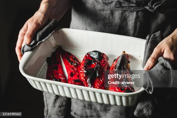 mulher chef com pimentões vermelhos assados na assadeira - pimentão vermelho assado - fotografias e filmes do acervo