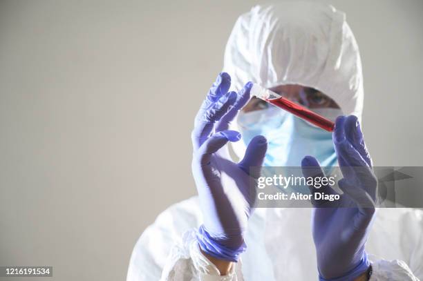 close up of medical sample in a lab which is just examining a scientist. he is wearing a protective mask, glasses and a protective suit (hazmat suit) - measuring cylinder stock pictures, royalty-free photos & images