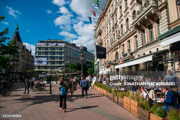 People sit in a restaurant in Stockholm on May 29 amid the coronavirus COVID-19 pandemic. - Sweden's two biggest opposition parties called Friday for...