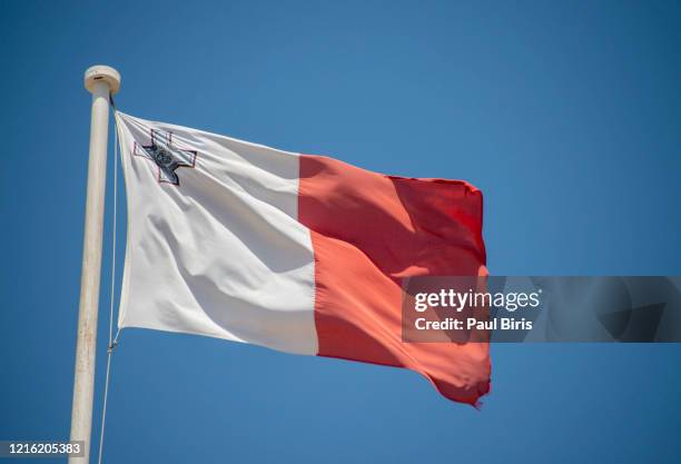 the flag of malta flying over a clear blue sky. - malta culture stock pictures, royalty-free photos & images