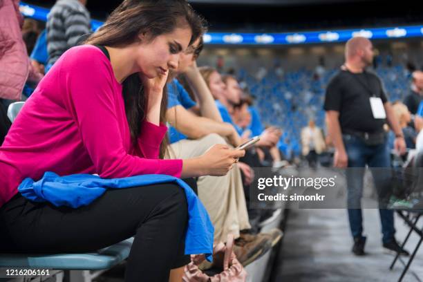 woman using smartphone in stadium - using phone stadium stock pictures, royalty-free photos & images