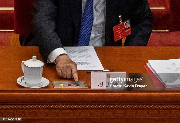 Chinese president Xi Jinping, reaches to press the green button as he votes on a new draft security bill for Hong Kong during the closing session of...