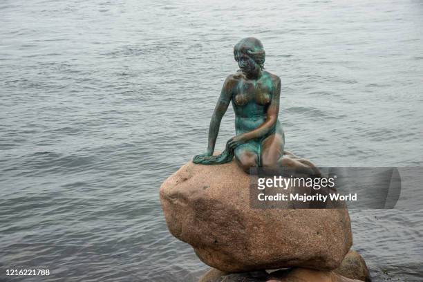 Sad looking mermaid sitting on a rock. The Little Mermaid, Den Lille Havfrue, Langelinie, Kobenhavn, Copenhagen, Denmark. Iconic bronze mermaid...