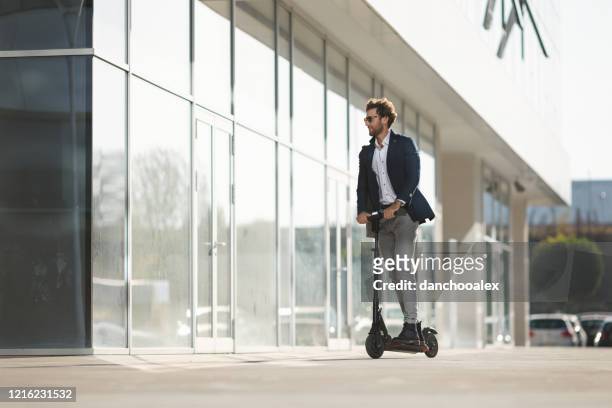 young businessman driving e-scooter in the city - scooter stock pictures, royalty-free photos & images
