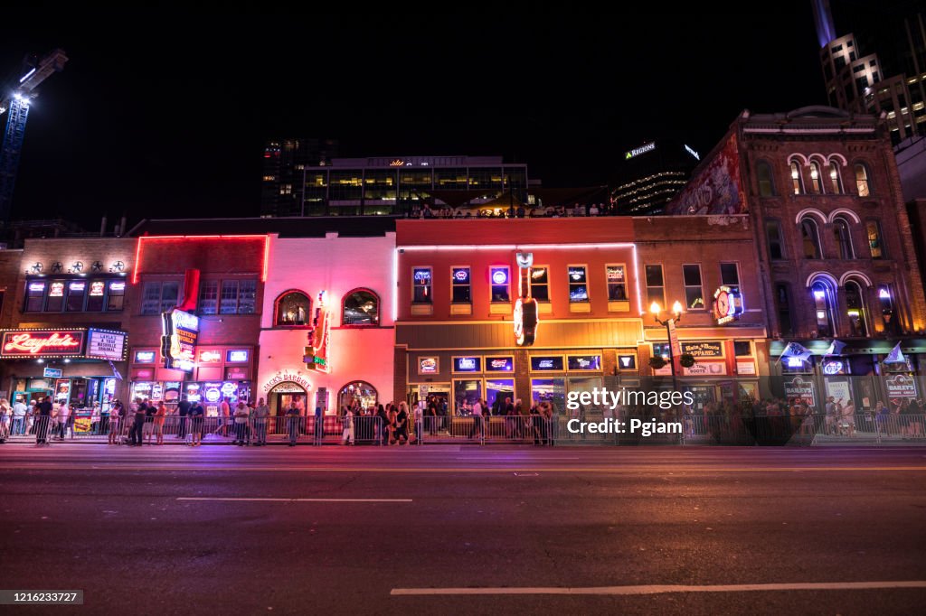 People walk along Broadway in Nashville Tennessee USA at night