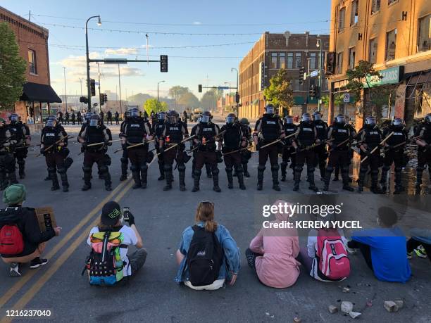 People sit on the street in front of a row of police officers during a rally in Minneapolis, Minnesota, on May 29, 2020 after the death of George...