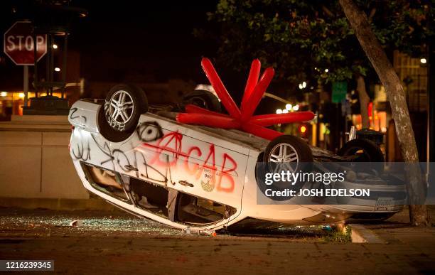 Vandalized car is flipped upside down as protesters face off against police in Oakland, California on May 29 during protests over the death of George...