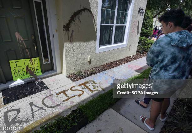 Demonstrator looks at the vandalism of a home owned by Derek Chauvin, the Minneapolis police officer videotaped kneeling on the neck of George Floyd...