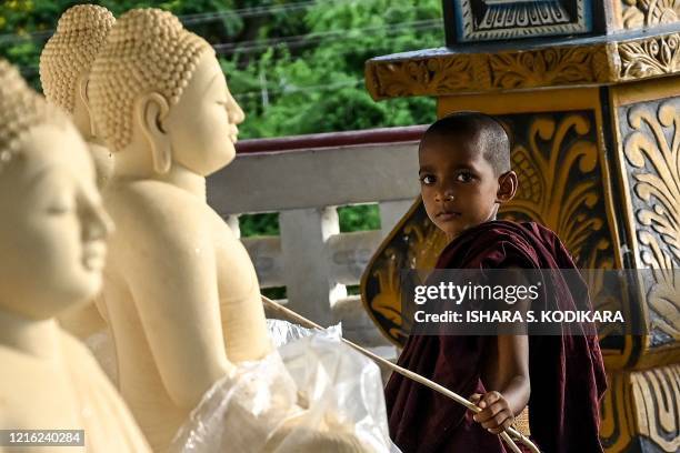 In this photo taken on May 29, 2020 a young monk poses at the Dimbulagala Raja Maha temple in the east of the island, on the eve of Buddhist 'Poson'...