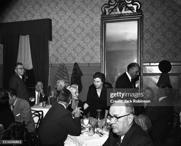 View of American restaurateur Ella Brennan speaks with Jazz and Pop vocalist Peggy Lee and an unidentified companion, seated at a table in Brennan's...