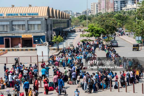 Migrant workers and their family members stand in a queue and waiting for the bus at Dharavi to go to Lokmanya tilak terminus as a special train...