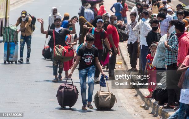 Migrant workers and their family members stand in a queue and waiting for the bus at Dharavi to go to Lokmanya tilak terminus as a special train...