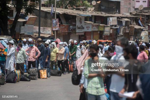 Migrant workers and their family members stand in a queue and waiting for the bus at Dharavi to go to Lokmanya tilak terminus as a special train...