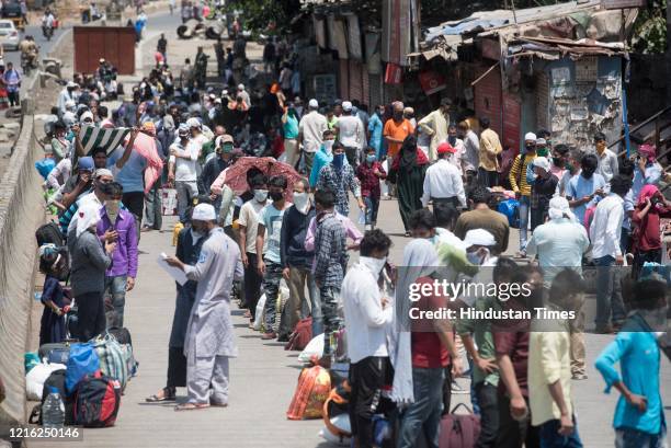 Migrant workers and their family members stand in a queue and waiting for the bus at Dharavi to go to Lokmanya tilak terminus as a special train...