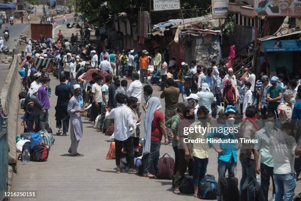 Migrant workers and their family members stand in a queue and waiting for the bus at Dharavi to go to Lokmanya tilak terminus as a special train...