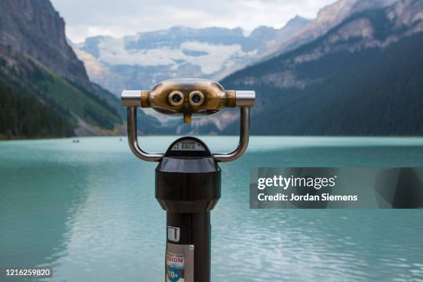 a pair of binoculars looking across lake louise. - coin operated binocular nobody stock pictures, royalty-free photos & images