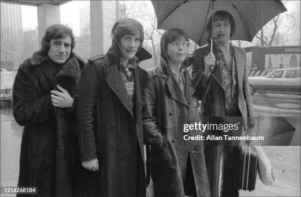 View of members of British comedy troupe Monty Python's Flying Circus as they stand in the rain on Central Park South, New York, New York, March 9,...