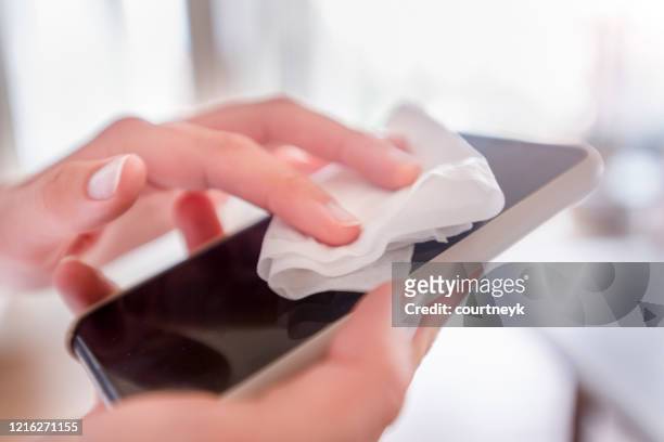 woman sanitizing her mobile phone. - rubbing stock pictures, royalty-free photos & images