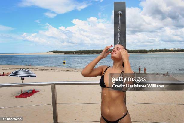 Olivia Woods rinses off after a quick swim at the usually bustling Bulcock Beach on March 31, 2020 in Caloundra, Australia. Public gatherings are now...