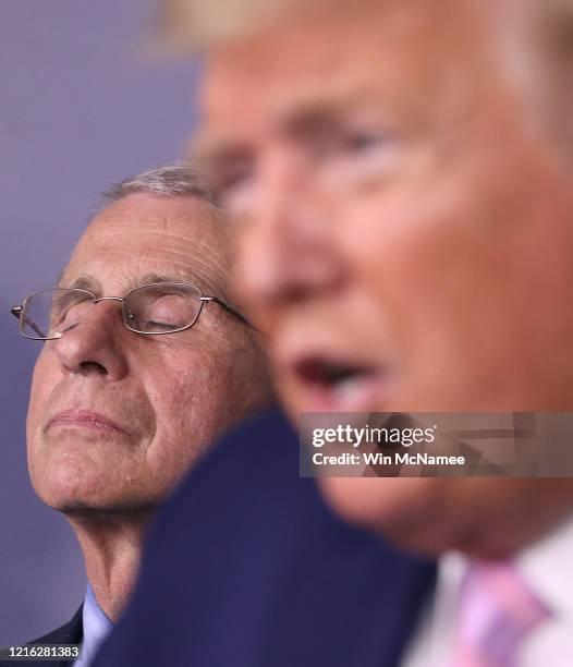 Dr. Anthony Fauci director of the National Institute of Allergy and Infectious Diseases, listens to U.S. President Donald Trump speak from the press...