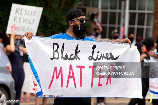 Man holds a Black Lives Matter banner during a racial justice protest in Charlottesville on May 30, 2020. - Demonstrations are being held across the...